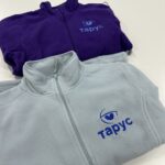 Сіра та фіолетова кофти з логотипом. Машинна вишивка на одязі та брендування корпоративного мерчу.