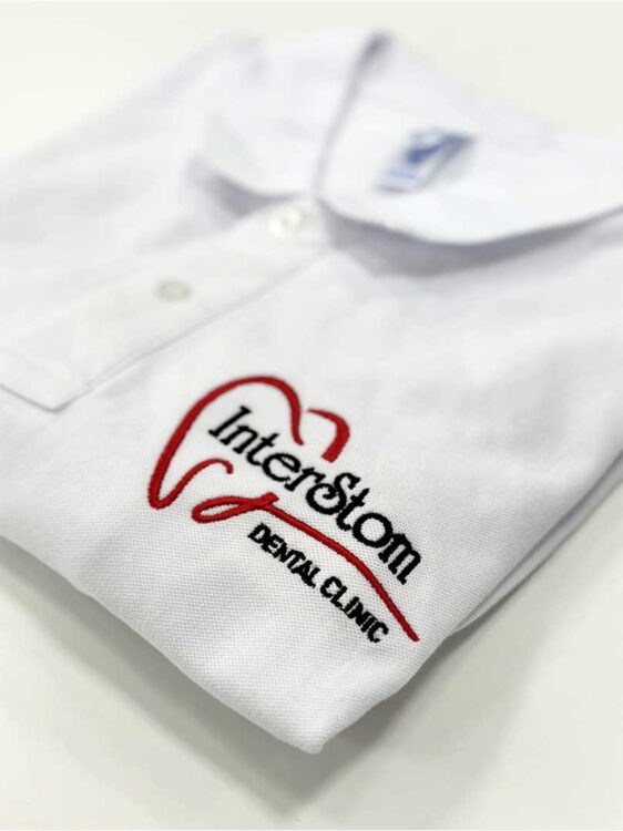 Вишивка логотипу на білій поло. Брендування одягу для стоматологічних клінік.
