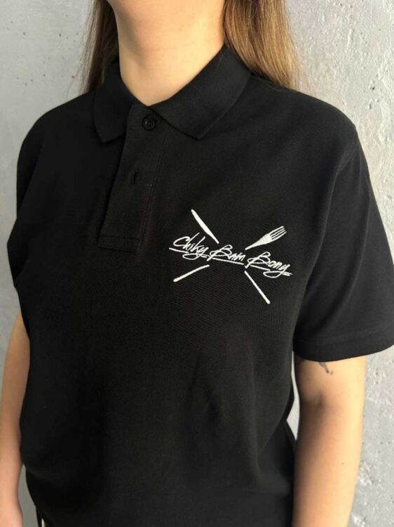 Брендування одягу для ресторанів: вишивка логотипу на чорній поло.