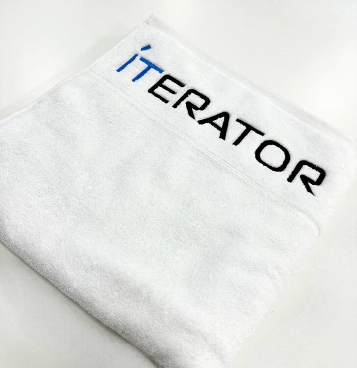 Вишивка логотипу на білому рушнику. Брендування текстилю для готелів або бізнесу.