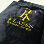 Чорний флісовий плед з вишитим логотипом компанії. Приклад брендування текстилю для подарунків та ресторанів.